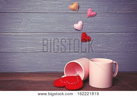 Two cups and color hearts on wooden background