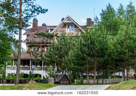 Valdaysky District, Russia - June 16, 2013: Large three-storey log house with veranda in the classical Russian style in the meadow among the trees by Andrey Kopylov, aka linkpusher