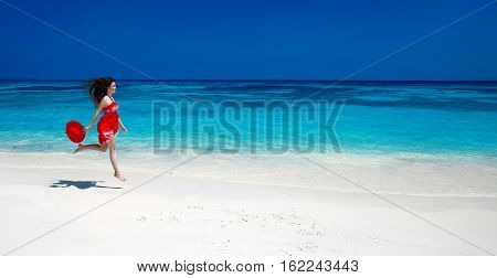 Summer Holiday. Happy Beautiful Woman Jumping On The Exotic Sea. Carefree Brunette Girl In Red Dress