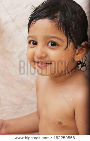 Happy baby in the bath wet hairs looking at camera shower photo