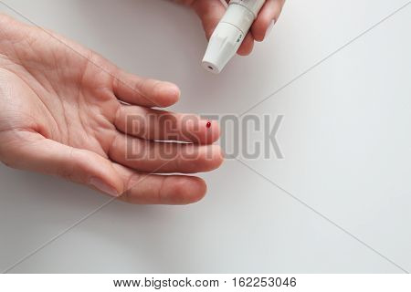 Woman using lancelet on finger