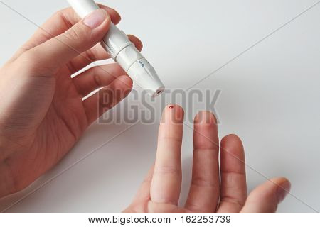 Woman using lancelet on finger