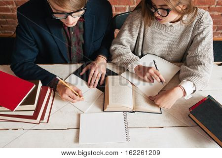Students man and woman recapitulate text top view. Studying in library, preparing for exams. Education, pair project, teamwork, brainstorm concept