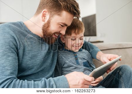 Picture of happy father using tablet computer with his little cute son.