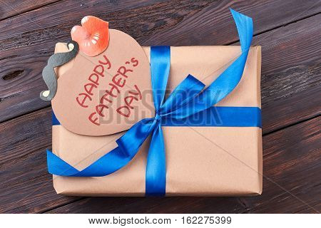 Card and gift for father. Present box on wooden backdrop. Support your dad.
