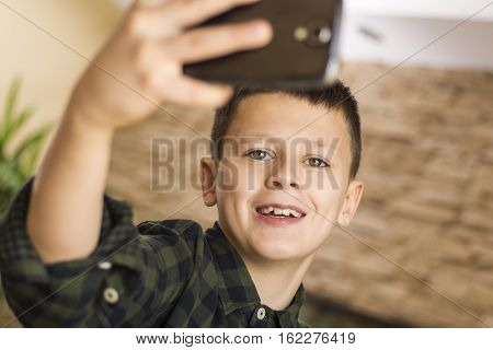 Young Boy Taking Selfie and Smiling at Home