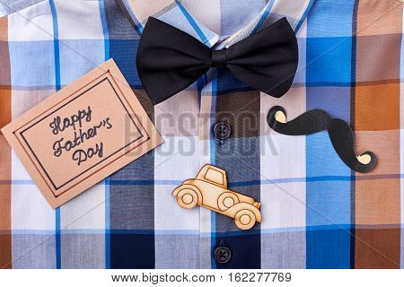 Checkered shirt and greeting card. Props mustache and bow tie. Congratulation with taste.