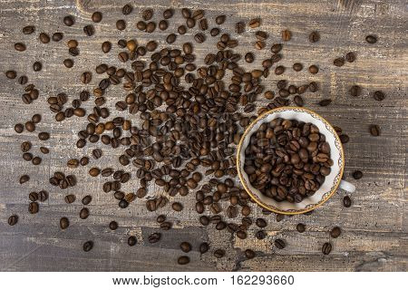 Coffee Cup spill the beans on a wooden table. A dark background. Blue drawing.