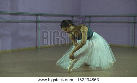 Young ballerina wears her pointe shoes in the classroom