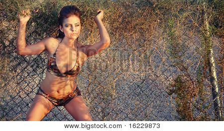Foto de beleza moda bikini exército de mulher posando ao lado de cerca