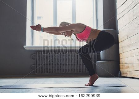 Young slim blond woman in yoga class making asana exercises. Girl do vinyasa transition to pose. Healthy lifestyle in fitness club. Stretching in standing position
