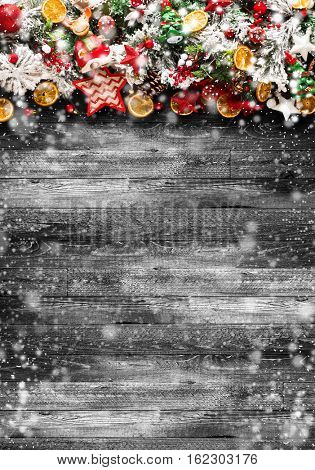Merry Christmas Frame with Snow and real wood green pine, colorful baubles, knots with berries,stars, orangesand other seasonal stuff over an old wooden aged background