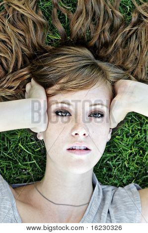 Attraktive Teenager weiblich liegend auf Gras mit schönen Haaren nachschlagen