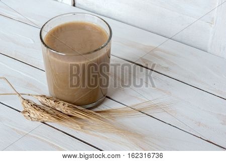 Traditional Drink from Balkan Peninsula Boza (fermented cereal beverage) and wheat over white wooden background