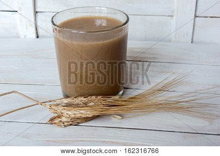 Traditional Drink from Balkan Peninsula Boza (fermented cereal beverage) and wheat over white wooden background