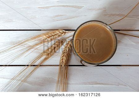 Traditional Drink from Balkan Peninsula Boza (fermented cereal beverage) and wheat over white wooden background