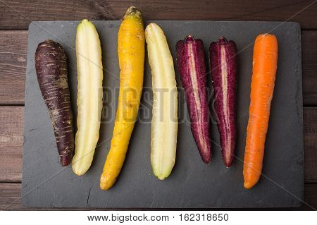 Fresh organic rainbow carrots on a wooden table and slate blackboard