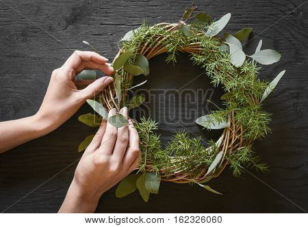 Hands making a wreath from eucalyptus and fir tree