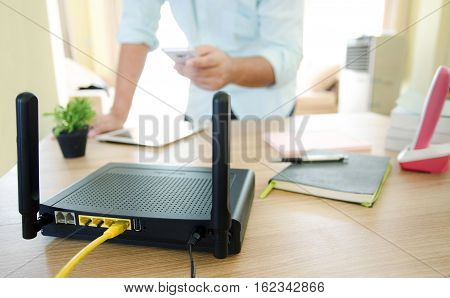 closeup of a wireless router and a man using smartphone on living room at home ofiice