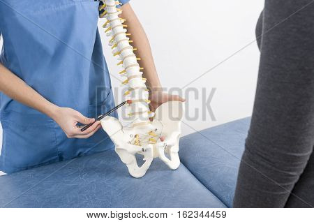 Doctor With A Pen Showing A Hernia In A Skeleton To A Patient.