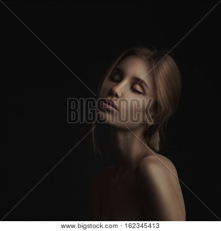 lowkey portrait of beautiful woman with closed eyes over dark background