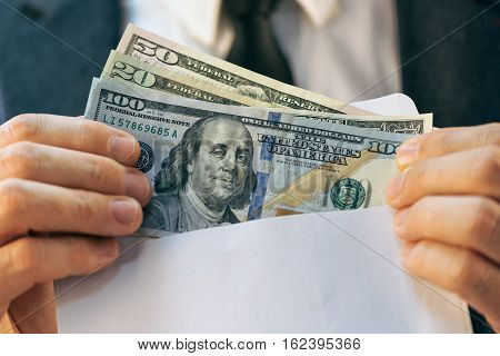 Bribery and corruption concept in business and politics with caucasian businessman and cash money in white envelope