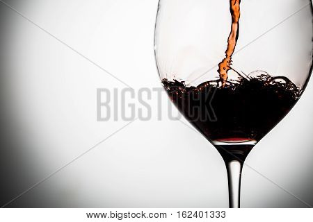 Wine poured into clear goblet on blank gray background