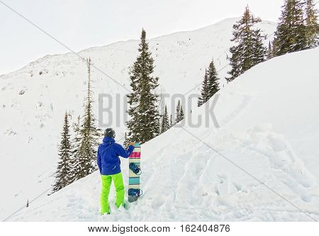 Freerider Man Is Standing On The Mountainside In A Helmet And With A Backpack And Looks Into The Dis