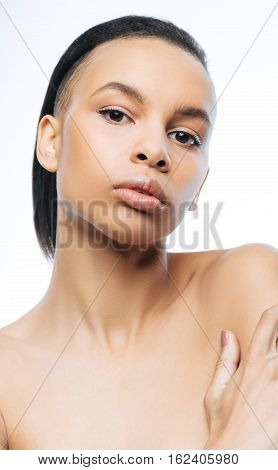 The beauty of my skin. Young graceful involved Negroid woman touching her skin while standing isolated in white background and expressing grace