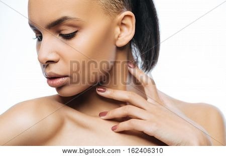 Full of passion. Elegant passionate young Negroid woman touching her neck while standing against white background and expressing passion