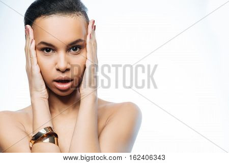 Emotions inside me. Surprised puzzled young Negroid woman touching her head while standing isolated in white background and expressing amazement