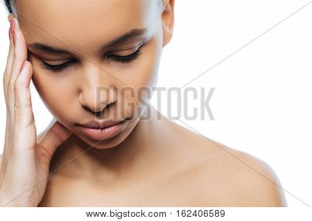Having a headache. Upset disappointed sad Negroid woman touching her head while standing against white background and suffering from a headache