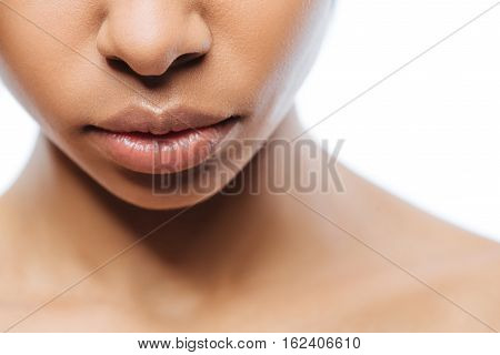 Soft full lips. Pleasant charming young Negroid woman standing against white background and expressing tenderness while demonstrating her full lips