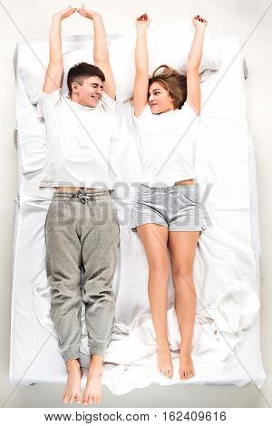 The young lovely couple lying in a white bed, love lconcept, top view