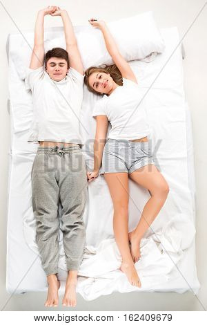 The young lovely couple lying in a white bed, love lconcept, top view