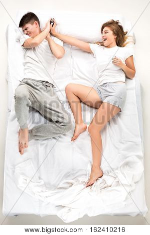 The young lovely couple lying in a white bed with alarm clock, love lconcept, top view