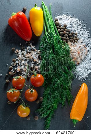 vegetables and spices on a black background, dill and pepper salt