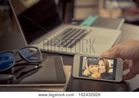 Office working Dad is looking for Motivation on his family photo in his smart phone.