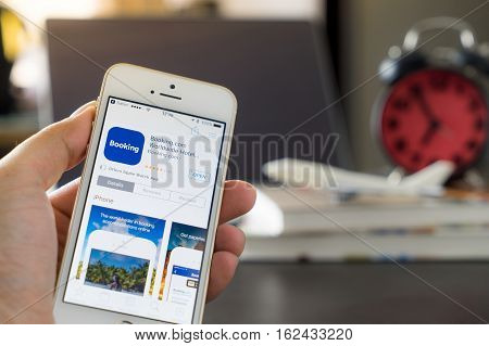 Bangkok, Thailand - March 10, 2017: Business man is using Booking.com application on his iPhone.