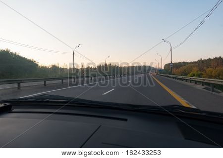 The view from the passenger car during autotravel early in the morning on an empty road