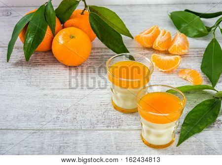 Delicious and rich in vitamins panna cotta with tangarine jam, tangarines and slice of tangarines on a white wooden table