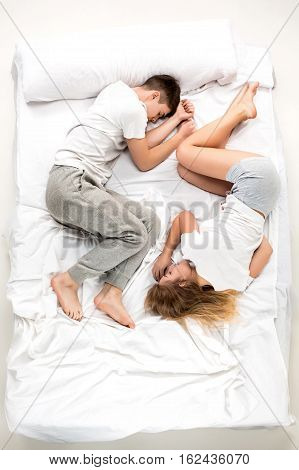 The young lovely couple lying in a white bed, love lconcept, top view
