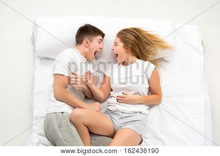 The young lovely couple lying in a white bed, love lconcept, top view