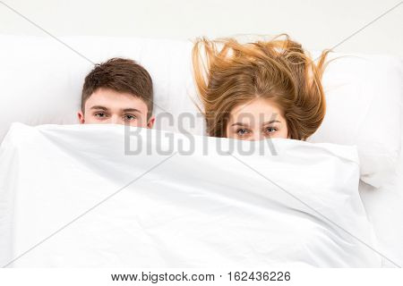 The young lovely couple lying in a white bed, love lconcept, top view