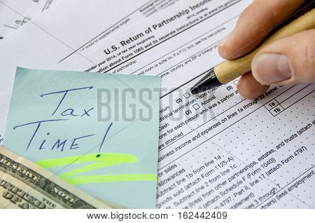 man filling Tax forms 1065 with dollar
