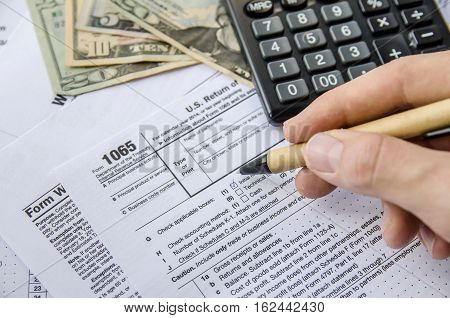 man filling Tax forms 1065 with calculator