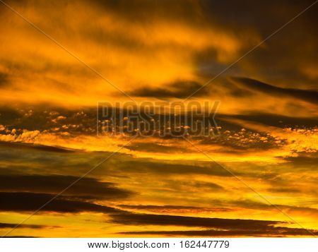 Dramatic golden sky with illuminated clouds at evening sunset time.