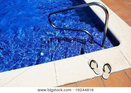 Close up di un paio di infradito su una piscina in estate