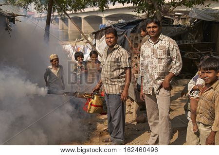 AHMADABAD, INDIA - OCTOBER 31, 2007: Men spraying insecticide powder amongst the dwellings of a shanty town Ahmadabad, Gujarat, India.
