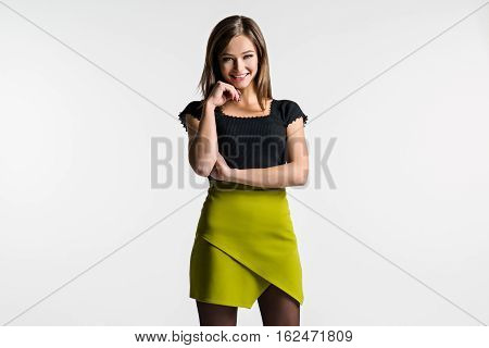 Beautiful woman posing on a light background. The green skirt